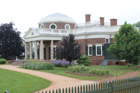 red brick with front white columns trim and flower beds